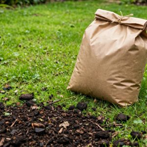 32 lb bag of milorganite fertilizer, slow-release nitrogen, beside compost on a lawn