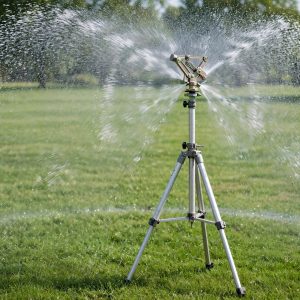 Tripod impact sprinkler spraying a wide circle over a large lawn