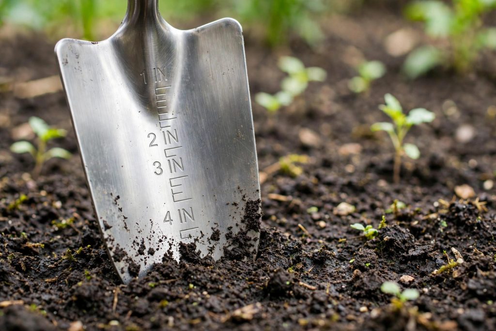 Garden trowel with depth markings pressed into soil